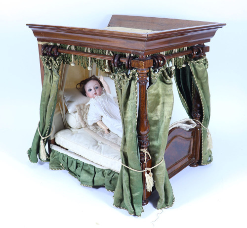 A good Victorian polished wood four poster dolls bed with green silk drapes,