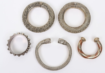 Pair of silver coloured metal African anklets embossed with geometric and flower head decoration and secure with pins