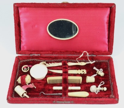 A good collection of miniature fashion doll accessories in a red velvet box, circa 1860,