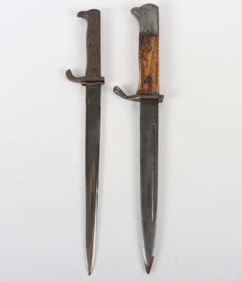Miniature German K98 Bayonet, with wooden grips, blade engraved 'Andenken an den Weltkrieg'. No scabbard. Accompanied by a smaller bronze miniature of a German bayonet with oakleaves relief to the hilt and body. Also without scabbard. (2 items) - 2