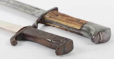 Miniature German K98 Bayonet, with wooden grips, blade engraved 'Andenken an den Weltkrieg'. No scabbard. Accompanied by a smaller bronze miniature of a German bayonet with oakleaves relief to the hilt and body. Also without scabbard. (2 items) - 7