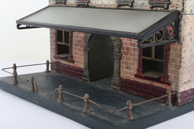 Bing 0 gauge Railway Station, brick effect building painted in shades of cream and orange, blue tiled effect roof, lithographed central arch and windows and glass tinplate framed canopy, 23.5cm wide, 22.5cm deep, 32cm high, fair condition, wear and paint - 7